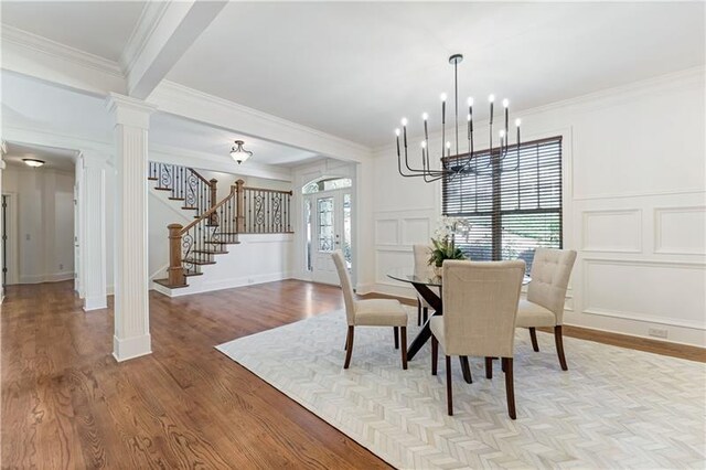 dining space with light wood-type flooring, ornate columns, crown molding, an inviting chandelier, and beamed ceiling