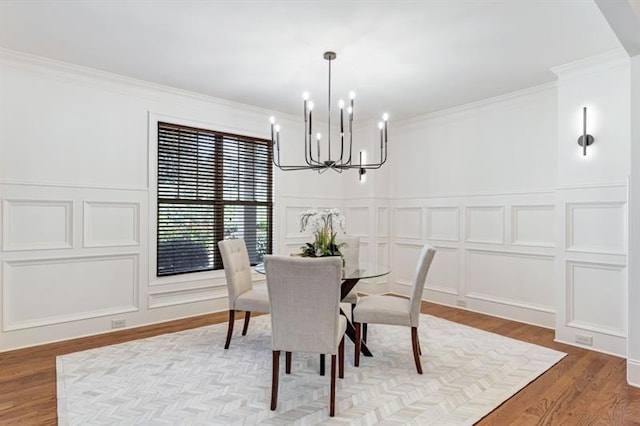 dining area with crown molding, a decorative wall, and wood finished floors