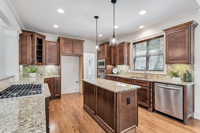 kitchen with sink, stainless steel appliances, light stone counters, light hardwood / wood-style floors, and decorative light fixtures