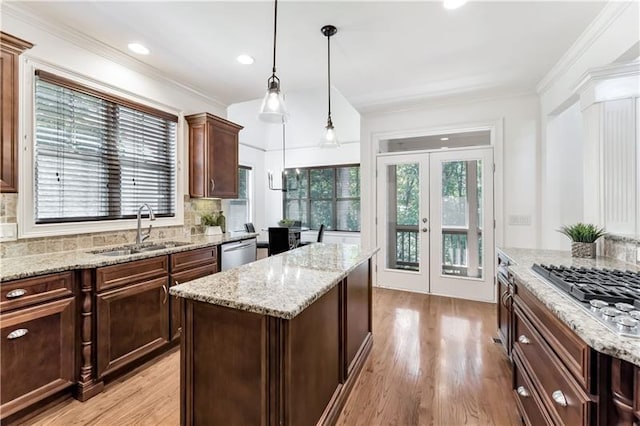 kitchen with decorative backsplash, appliances with stainless steel finishes, sink, pendant lighting, and a center island