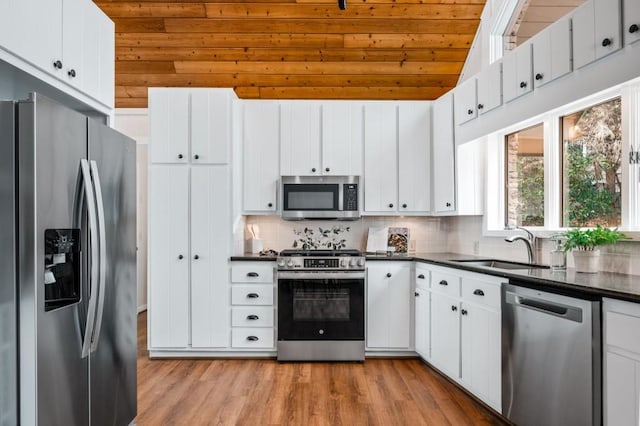 kitchen featuring a sink, white cabinets, appliances with stainless steel finishes, decorative backsplash, and dark countertops