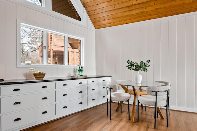 dining area with light wood-type flooring, a healthy amount of sunlight, wooden ceiling, and vaulted ceiling