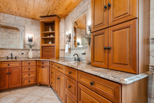 kitchen featuring brown cabinetry, wooden ceiling, a sink, and light stone countertops