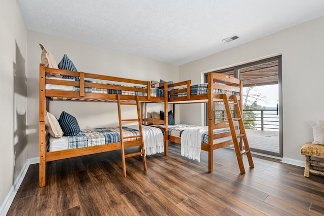 bedroom featuring visible vents, baseboards, a textured ceiling, and wood finished floors