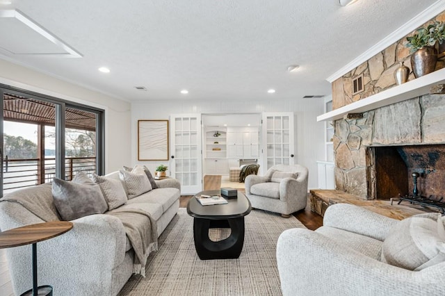 living room featuring wood finished floors, a textured ceiling, french doors, a fireplace, and recessed lighting