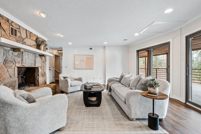 living room with a fireplace, a textured ceiling, crown molding, and wood finished floors