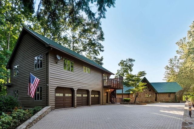 view of front facade with a deck, decorative driveway, stairway, and an attached garage