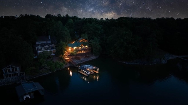 aerial view at night featuring a water view