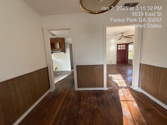 spare room with a wainscoted wall, wooden walls, and dark wood finished floors