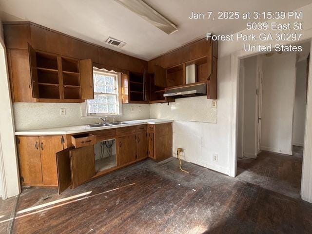 kitchen featuring visible vents, dark wood-style floors, wall chimney exhaust hood, open shelves, and a sink