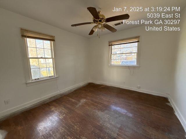 spare room featuring a wealth of natural light, visible vents, baseboards, and wood finished floors