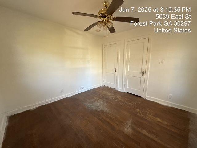 unfurnished bedroom with dark wood-style flooring, a ceiling fan, and baseboards