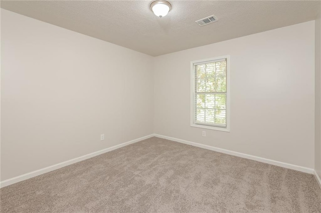 spare room with light carpet and a textured ceiling