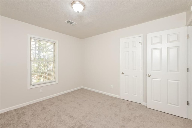 unfurnished bedroom with a textured ceiling and light carpet