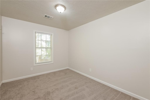 unfurnished room featuring light carpet and a textured ceiling