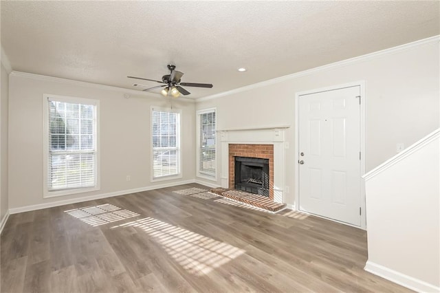 unfurnished living room featuring hardwood / wood-style flooring, ceiling fan, crown molding, and a brick fireplace