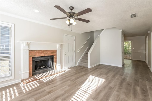 unfurnished living room featuring a fireplace, a textured ceiling, hardwood / wood-style flooring, and ceiling fan