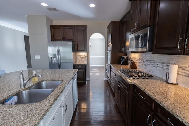 kitchen featuring appliances with stainless steel finishes, light stone counters, dark hardwood / wood-style floors, sink, and tasteful backsplash