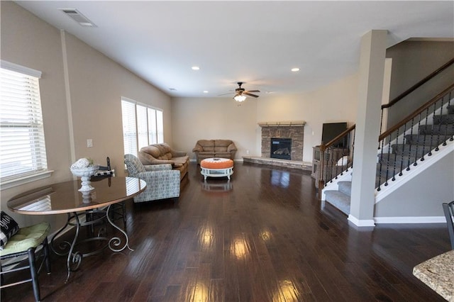 living room with dark hardwood / wood-style flooring and a stone fireplace