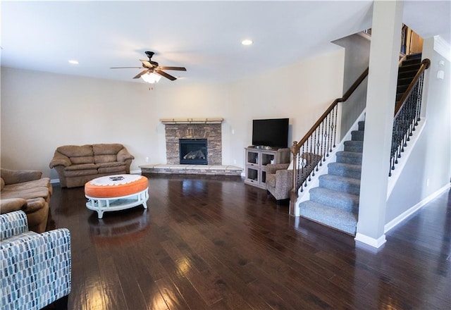 living room featuring ceiling fan, dark hardwood / wood-style flooring, and a fireplace