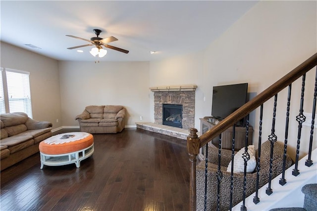 living room featuring hardwood / wood-style floors, ceiling fan, and a stone fireplace