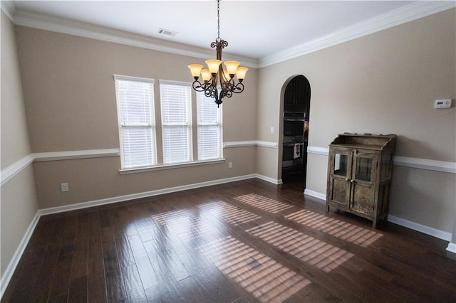 empty room featuring ornamental molding, a notable chandelier, and dark hardwood / wood-style flooring