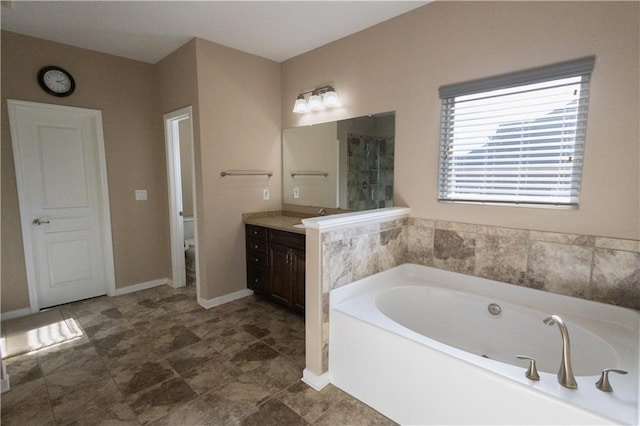 bathroom with toilet, vanity, and a tub to relax in