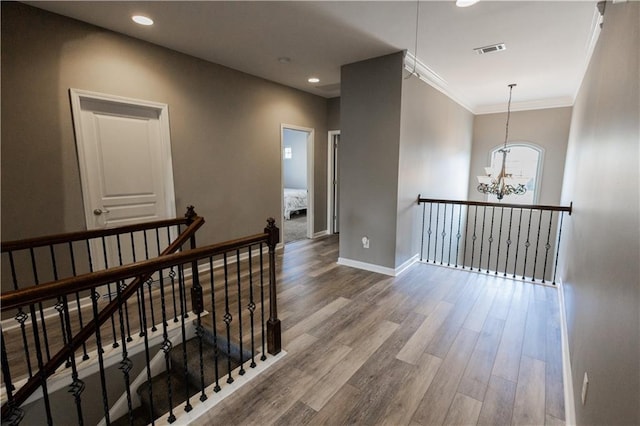 hall featuring ornamental molding, hardwood / wood-style floors, and a notable chandelier