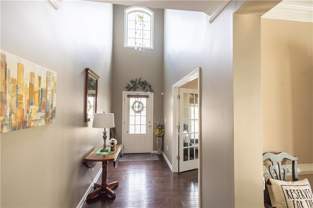 entryway featuring a high ceiling, dark wood-type flooring, and ornamental molding