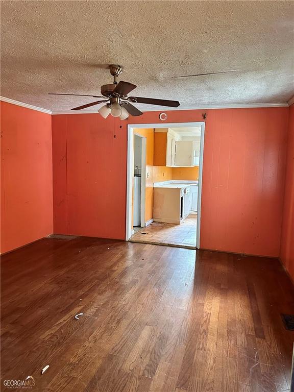 spare room featuring crown molding, a ceiling fan, a textured ceiling, and light wood-type flooring