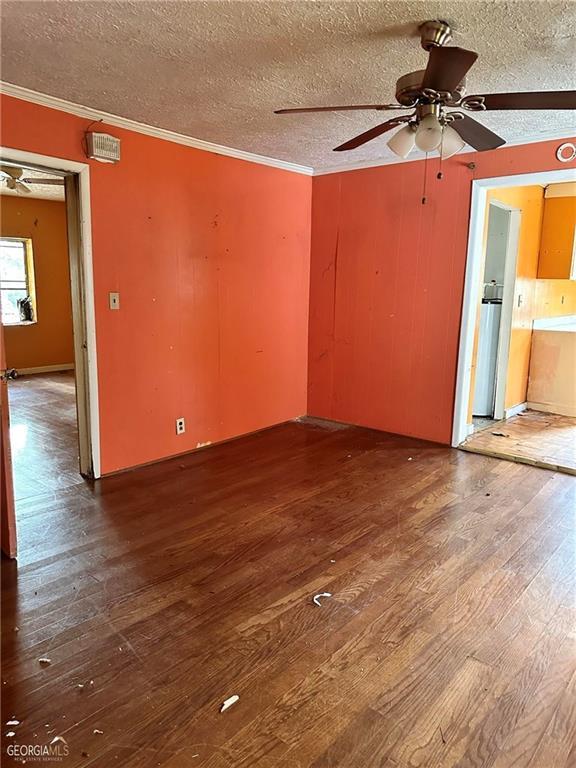spare room featuring crown molding, a ceiling fan, a textured ceiling, and wood finished floors