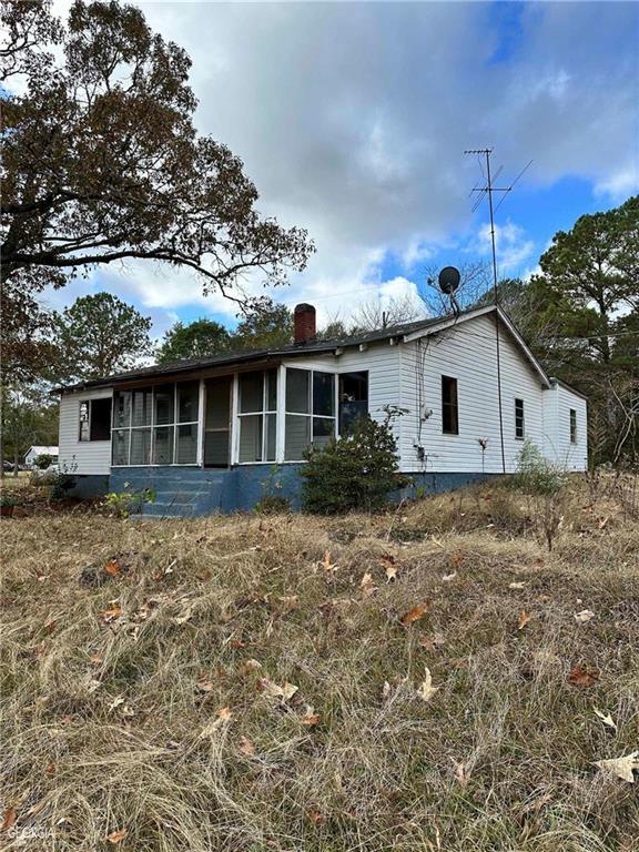 rear view of property with a chimney and a sunroom