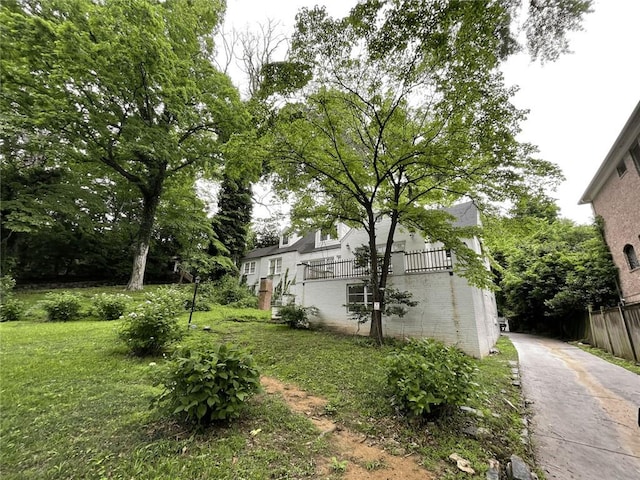view of side of property with a lawn, fence, brick siding, and driveway