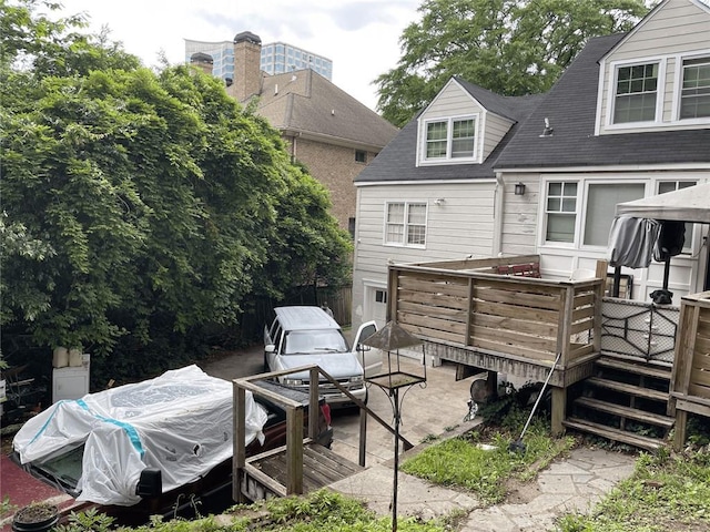 rear view of property featuring roof with shingles and a deck