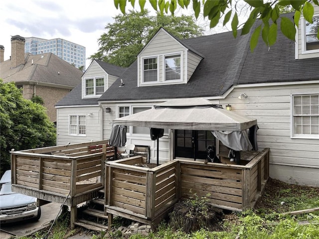 back of house featuring a deck and a shingled roof