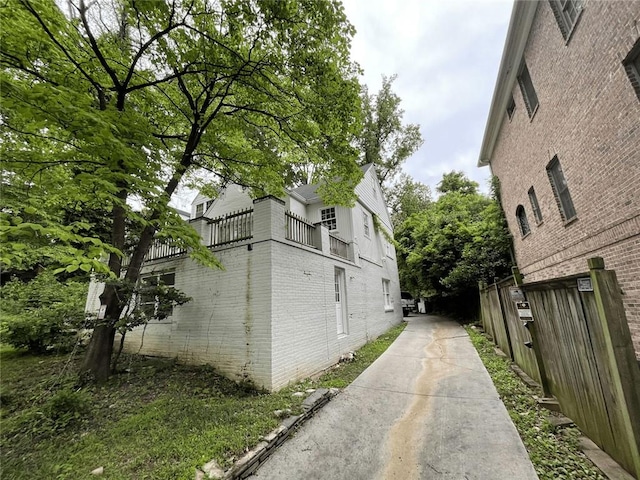 view of home's exterior featuring fence, brick siding, and a balcony