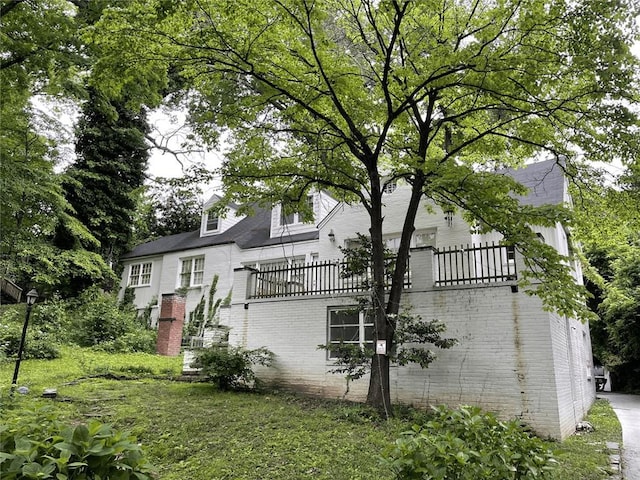 view of side of home with a balcony and brick siding
