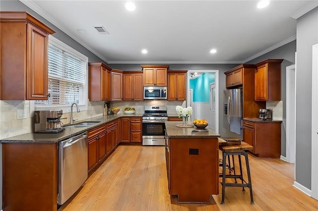 kitchen featuring a center island, sink, appliances with stainless steel finishes, light hardwood / wood-style floors, and a kitchen bar