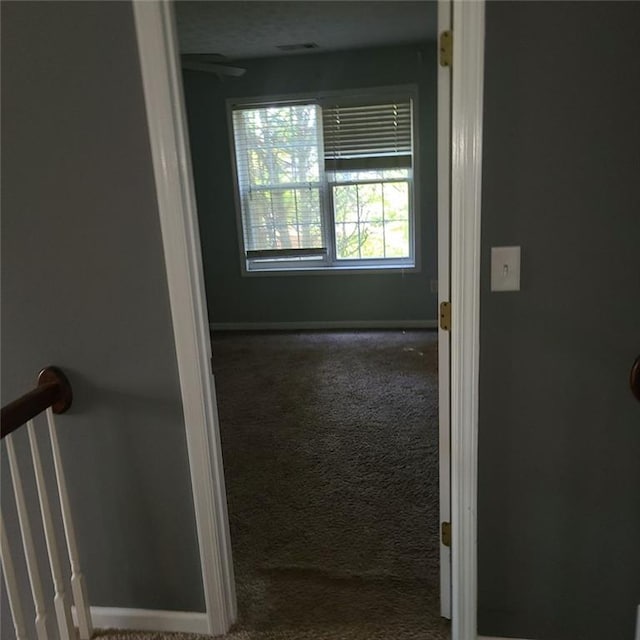 corridor with carpet flooring and a textured ceiling