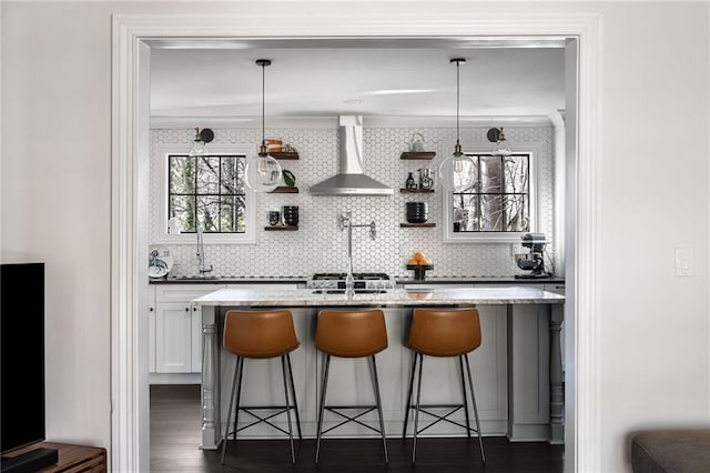 bar with wall chimney exhaust hood, hanging light fixtures, dark wood finished floors, and decorative backsplash