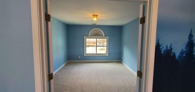 carpeted spare room featuring baseboards