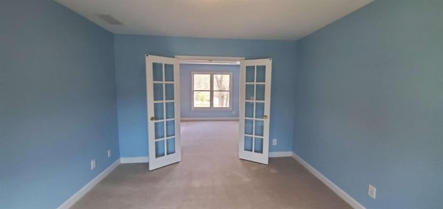 carpeted empty room with baseboards, visible vents, and french doors