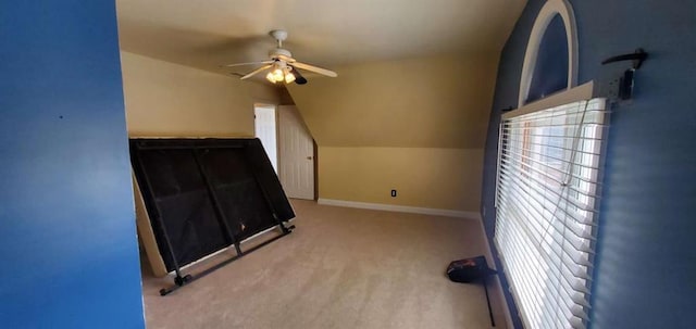 interior space featuring lofted ceiling, carpet flooring, a ceiling fan, and baseboards