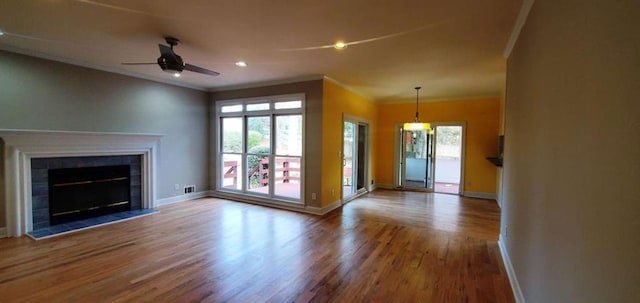 unfurnished living room featuring ornamental molding, a fireplace, baseboards, and wood finished floors