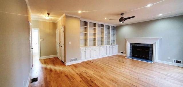 unfurnished living room featuring a ceiling fan, a tile fireplace, light wood-type flooring, and visible vents