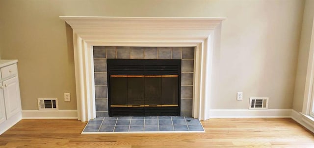 details featuring baseboards, a fireplace, visible vents, and wood finished floors