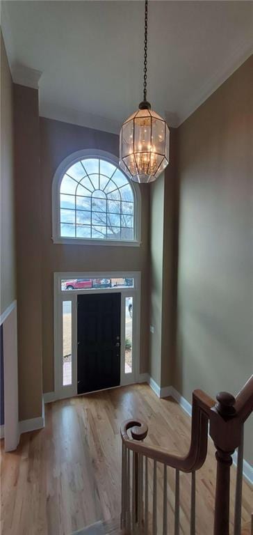 foyer featuring a chandelier, ornamental molding, light wood-type flooring, and baseboards