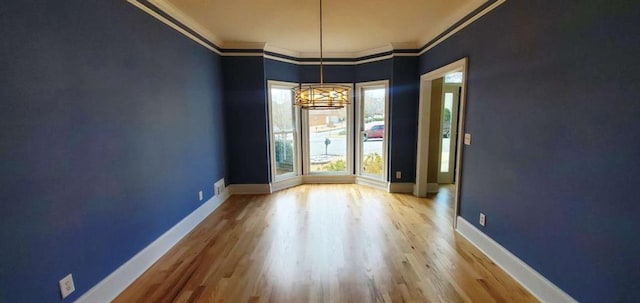 unfurnished room featuring crown molding, baseboards, and wood finished floors