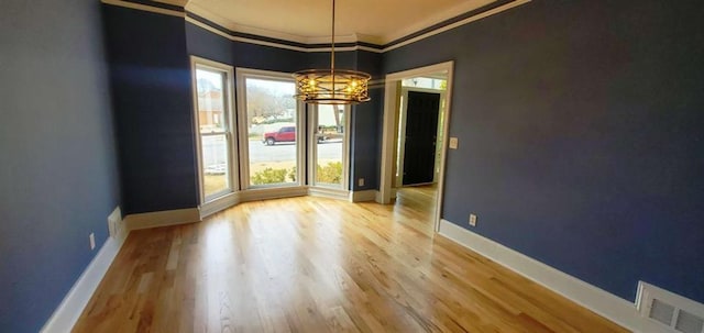 unfurnished room featuring visible vents, baseboards, ornamental molding, wood finished floors, and a notable chandelier