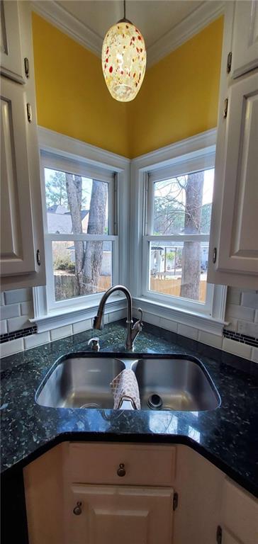 kitchen featuring crown molding, dark stone countertops, and a sink